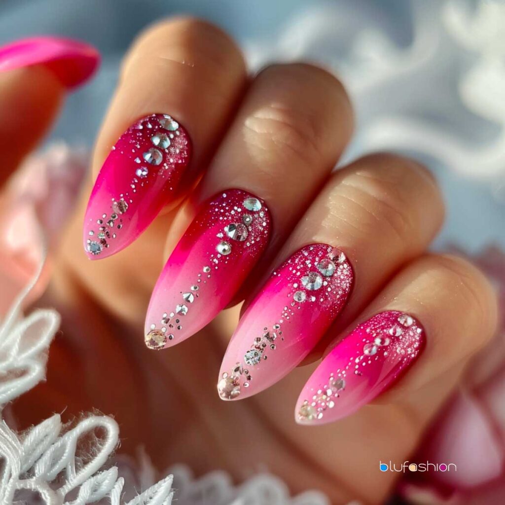 Ongles aiguilles rose vif dégradés avec une cascade étincelante de paillettes argentées et de strass diamantés, créant une manucure glamour et accrocheuse.